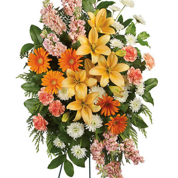 Standing floral spray with yellow lilies, orange daisies, and pink carnations