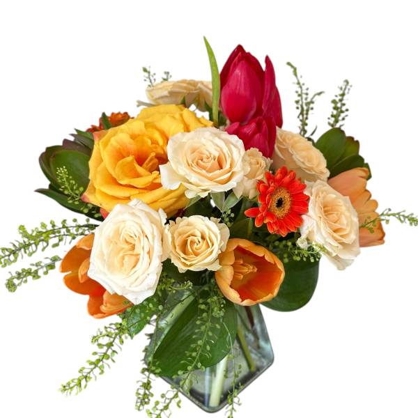Mixed bouquet of roses, tulips, and a gerbera daisy in a glass vase