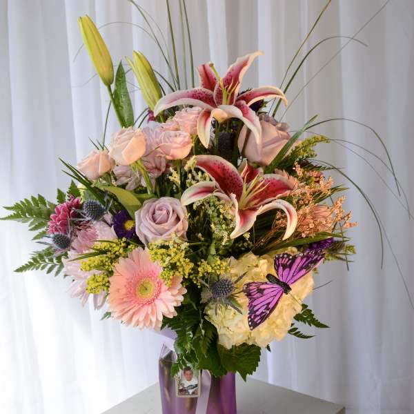 Mixed bouquet with pink lilies, roses, and a purple vase
