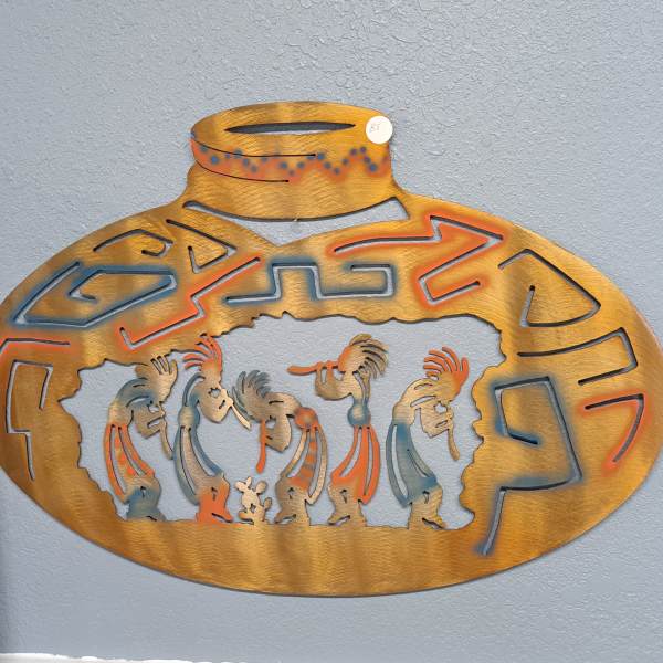 Decorative metal wall art with stylized figures in an oval frame