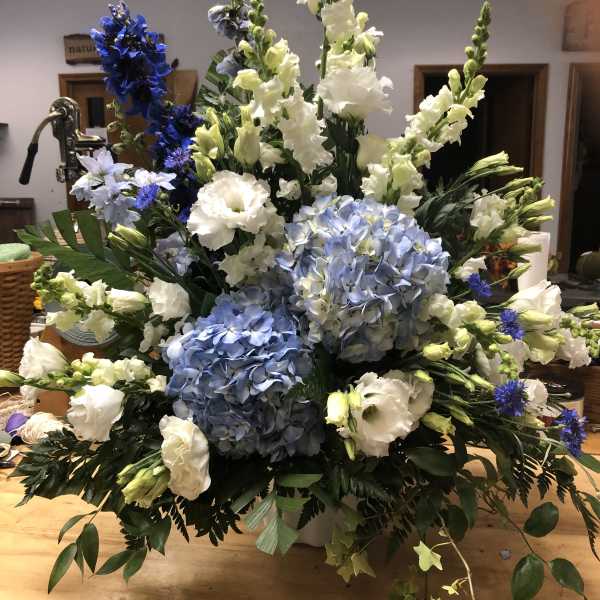 Large blue and white floral arrangement with tall spikes and hydrangeas