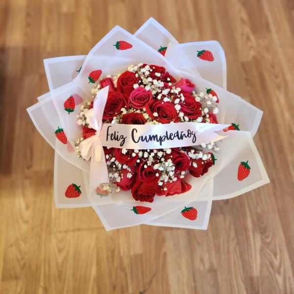 Red rose bouquet wrapped in strawberry-patterned paper with a birthday ribbon