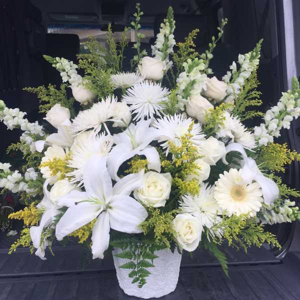 White floral arrangement in a textured white vase with lilies and roses