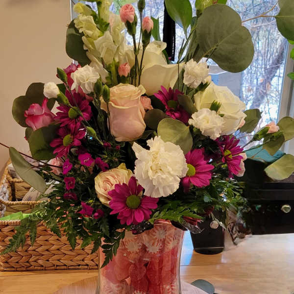 Mixed bouquet of pink, white, and magenta flowers in a clear glass vase