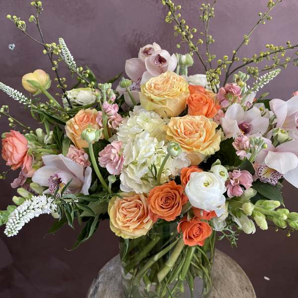 Mixed bouquet of roses, orchids, and hydrangea in a glass vase