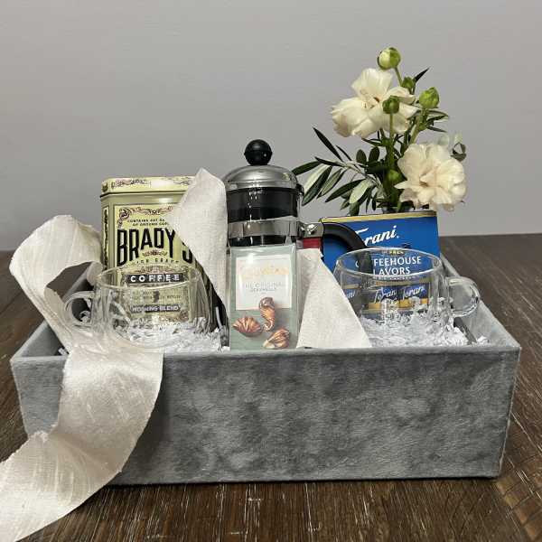 Gift basket with coffee, mugs, tea, and white flowers