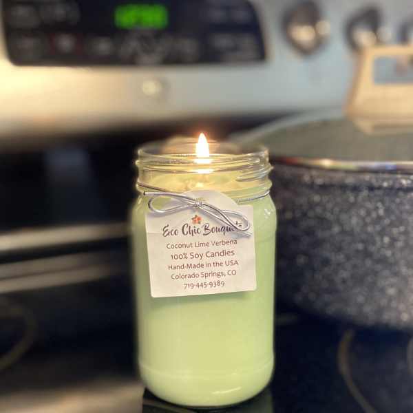 Lit green candle in a glass jar with a hanging label