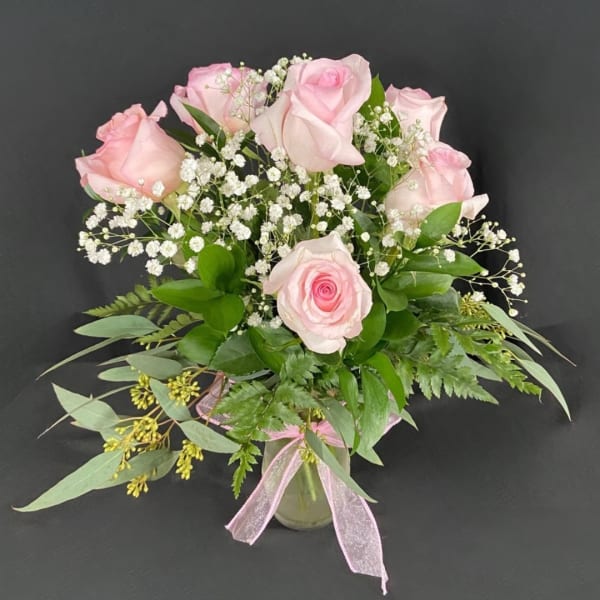 Pink roses in a glass vase with baby's breath and greenery