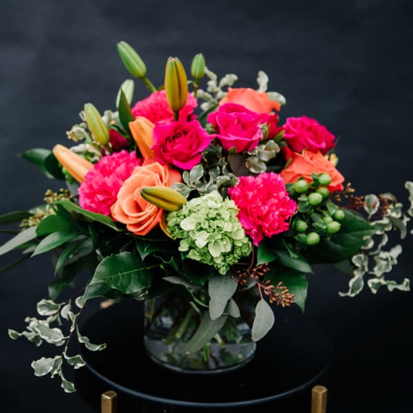 Bright mixed bouquet in a glass vase with pink and peach blooms