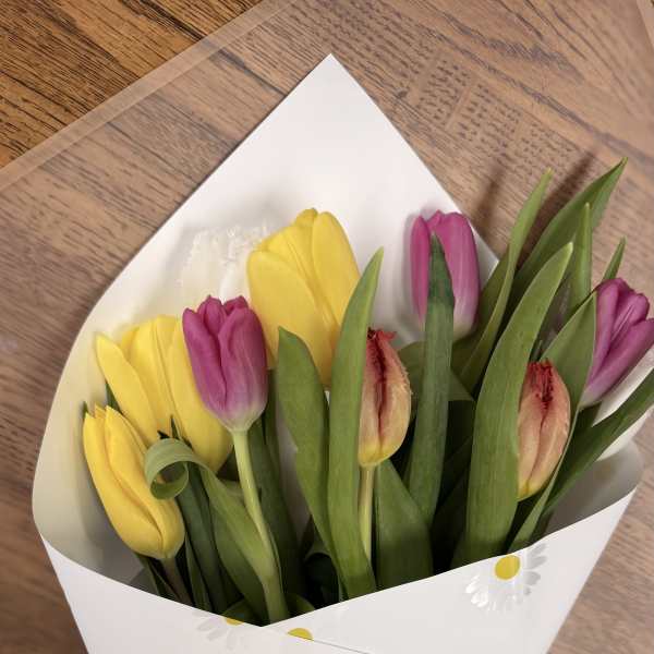 Bouquet of yellow and pink tulips wrapped in white paper