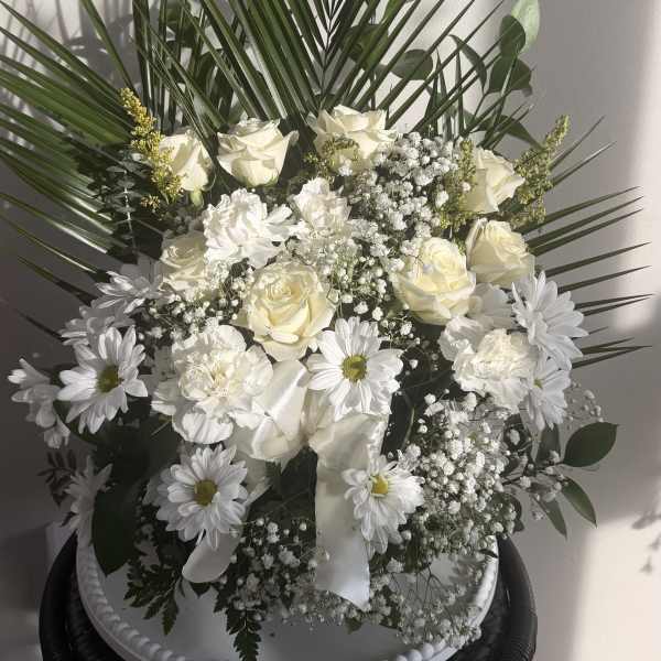 White floral arrangement with roses and daisies in a white container