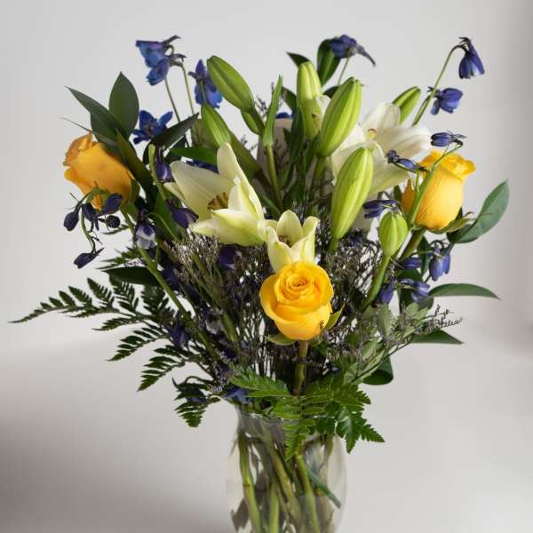 Yellow roses and white lilies in a clear glass vase