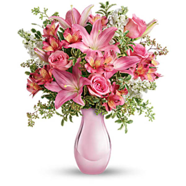 Pink lilies and roses arranged in a pink glass vase