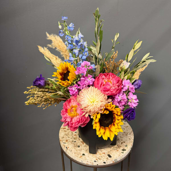 Colorful mixed bouquet in a black vase with sunflowers and pink blooms