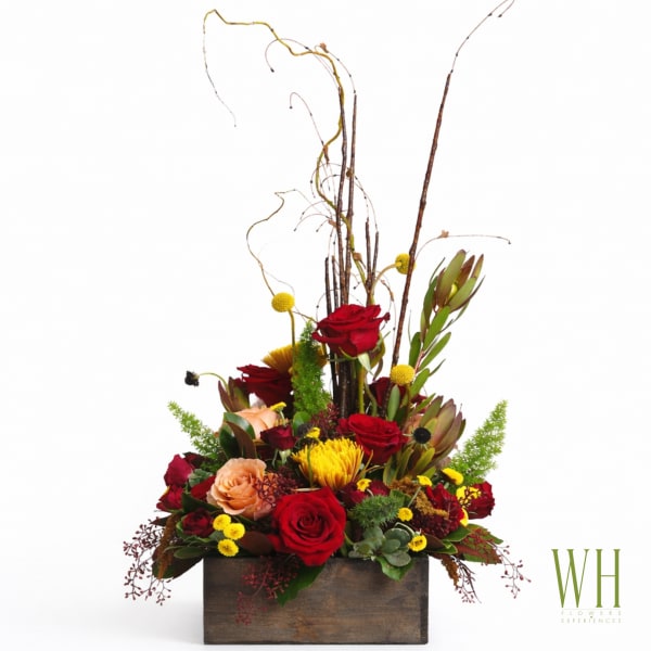 Tall floral arrangement with red roses and yellow blooms in a wooden box