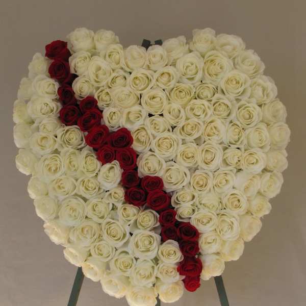 Heart-shaped rose arrangement with a red diagonal stripe on an easel