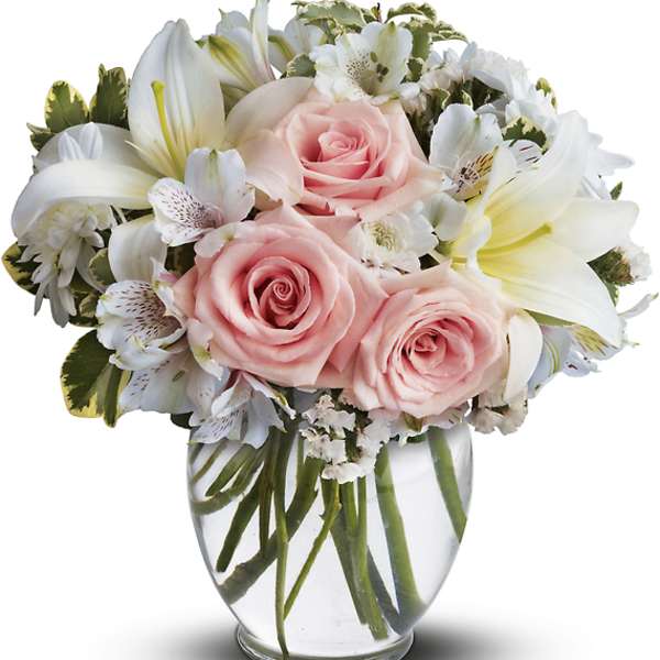 Pink roses and white lilies arranged in a clear glass vase