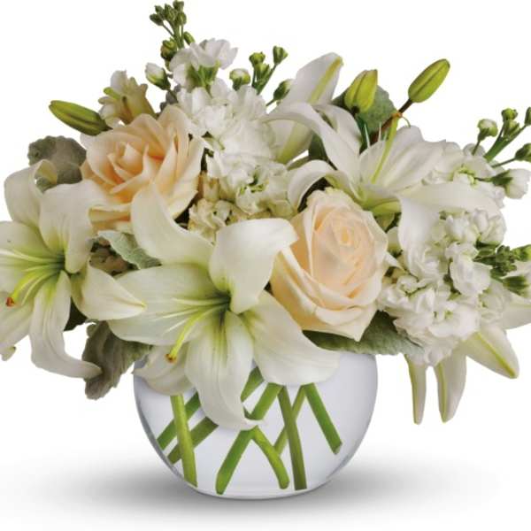White lilies and cream roses arranged in a round glass vase