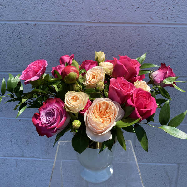 Bouquet of pink, peach, and lavender roses in a clear vase
