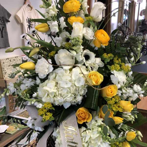 Tall floral spray with yellow roses and white blooms on a ribboned stand