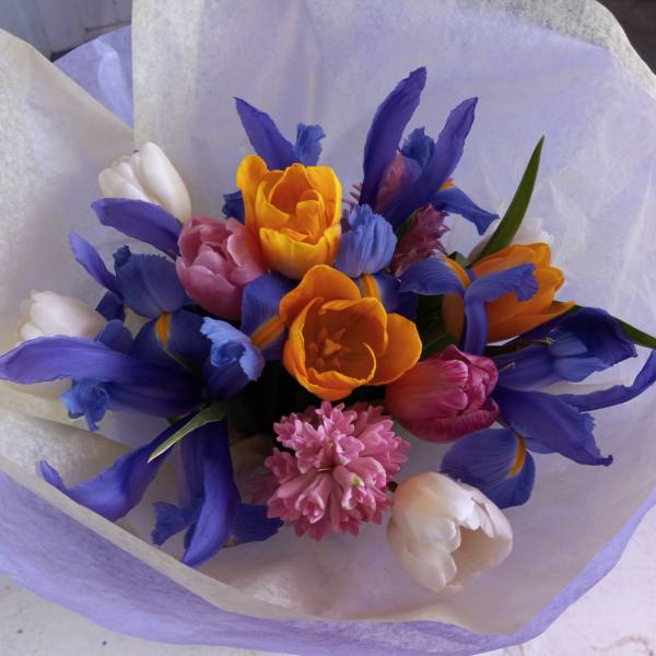 Bouquet of purple, orange, pink, and white tulips wrapped in pale paper
