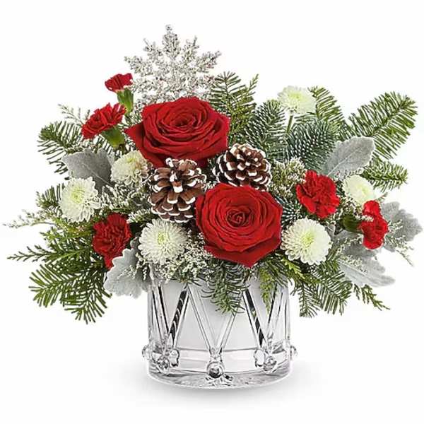 Red roses and white flowers in a clear glass vase with pinecones