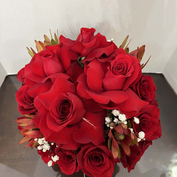 Round bouquet of red roses with small white filler flowers