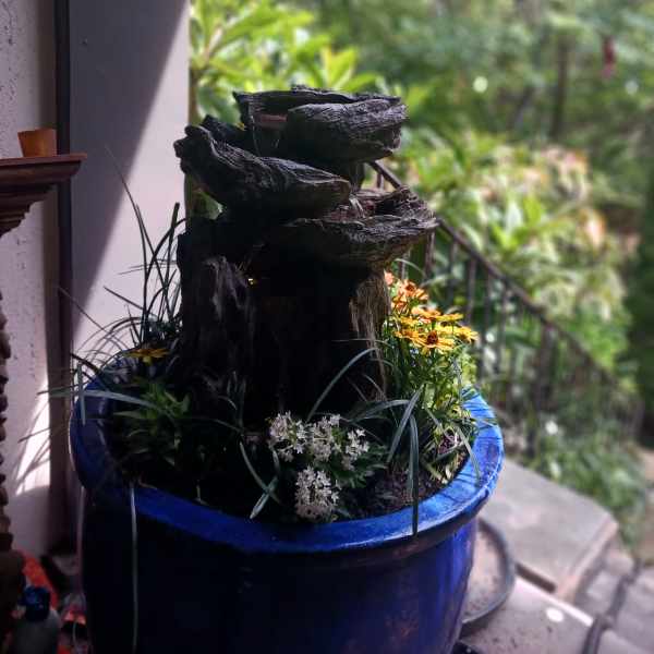 Blue planter with a small rock fountain and mixed flowers