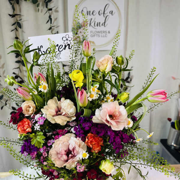 Mixed bouquet of tulips, roses, and small daisies in a gold vase