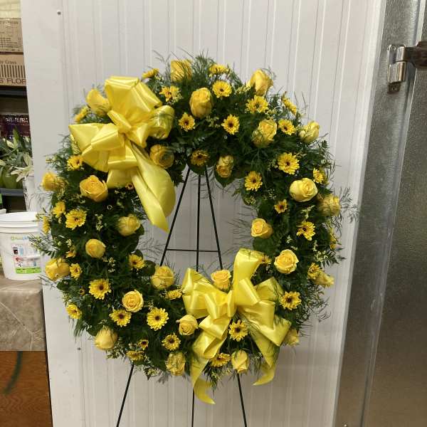 Yellow rose and daisy wreath on a standing easel with ribbon bows