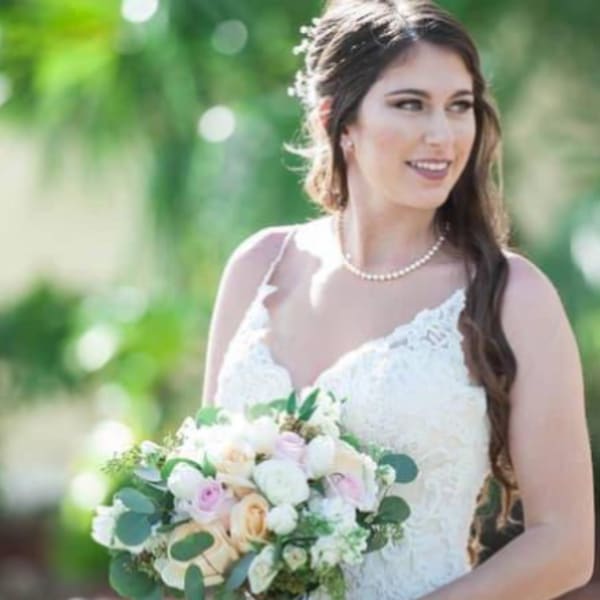 Bride holding a pastel bouquet of roses and white flowers