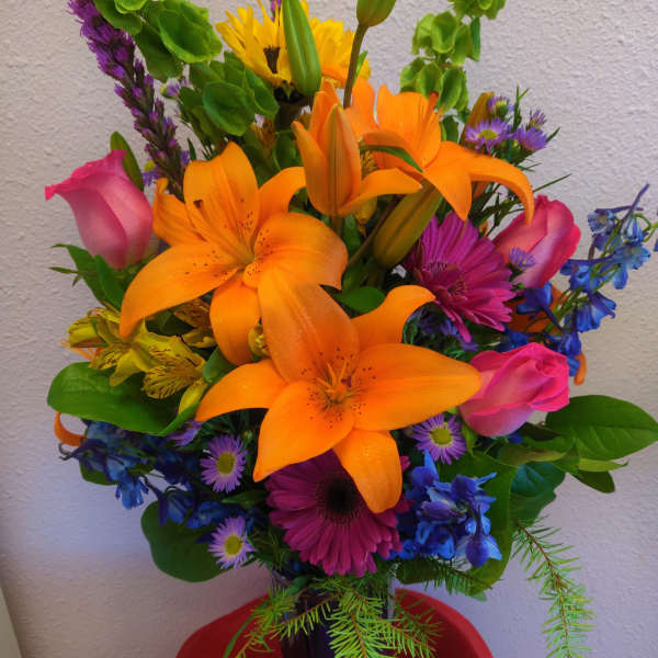 Colorful bouquet with orange lilies, pink roses, and purple flowers in a vase