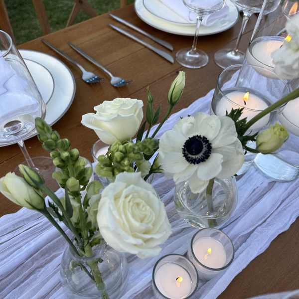 White floral centerpieces with candles on a set dining table