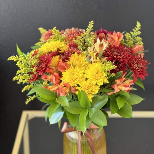 Bouquet of yellow, red, and orange flowers in a ribbed glass vase
