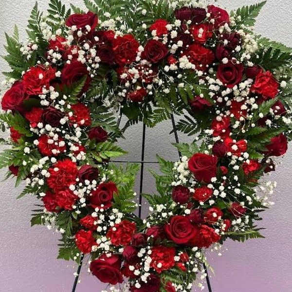 Heart-shaped wreath of red roses and white baby's breath on a stand
