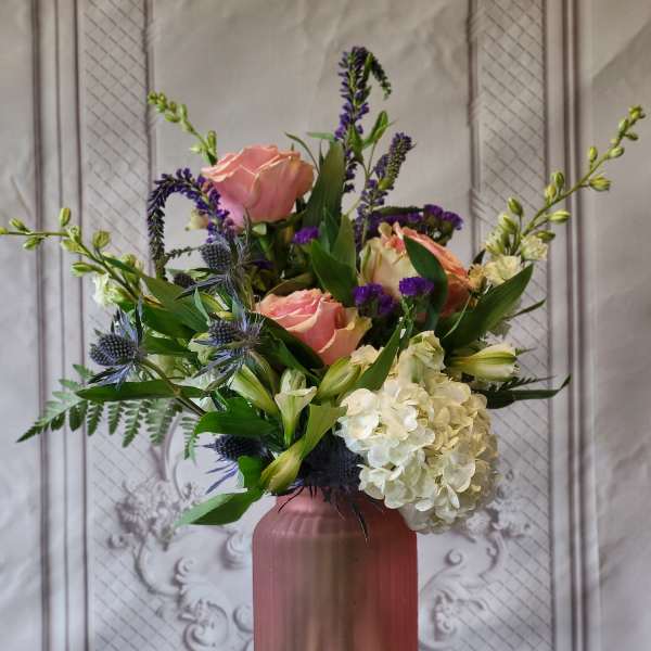 Pink roses and white hydrangea in a mauve vase