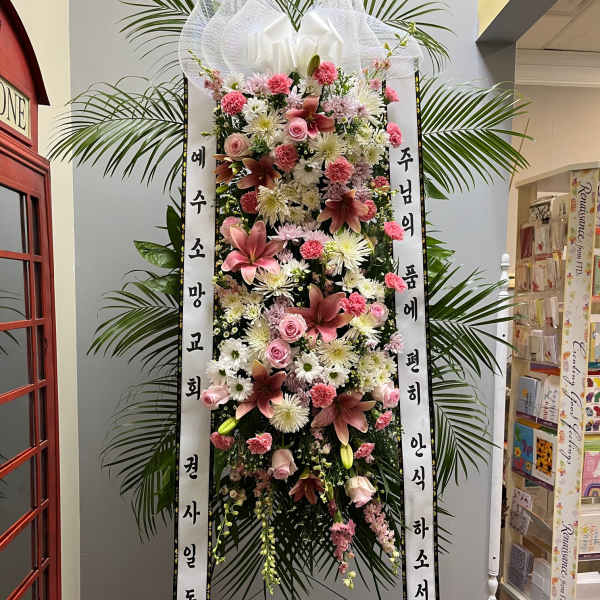 Tall standing floral wreath with pink and white flowers and Korean condolence ribbons
