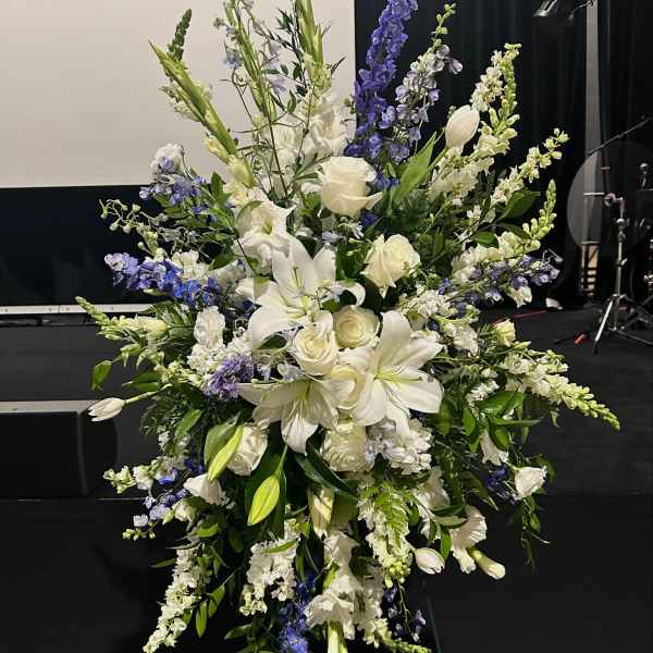 Tall white and blue floral standing spray on an easel