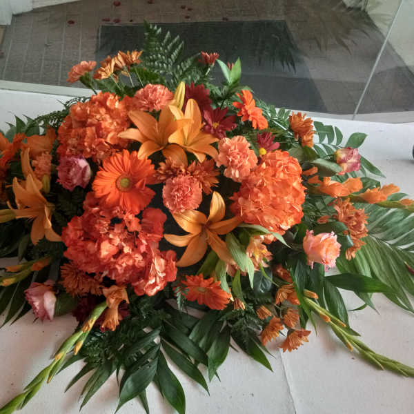 Large orange floral arrangement with lilies, daisies, and carnations
