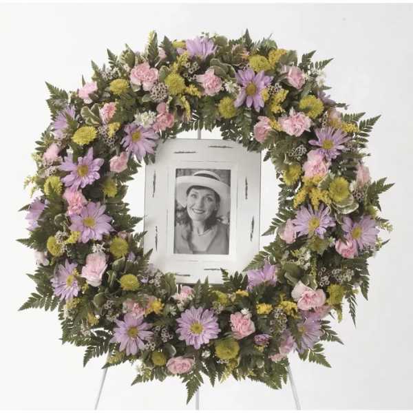 Floral wreath with pink and lavender flowers around a framed photo