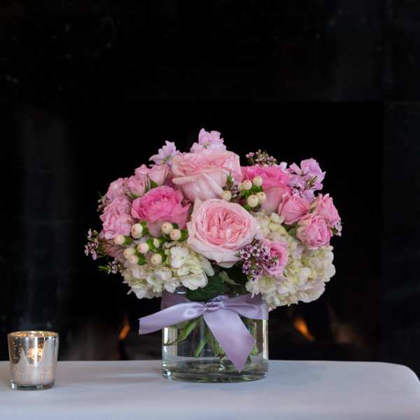 Pink rose bouquet in a glass vase with a lavender ribbon