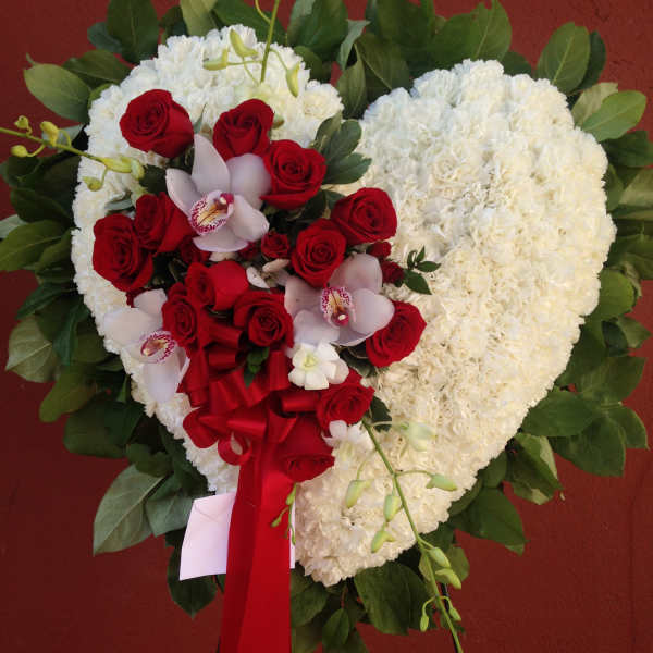 Heart-shaped white floral arrangement with red roses and orchids