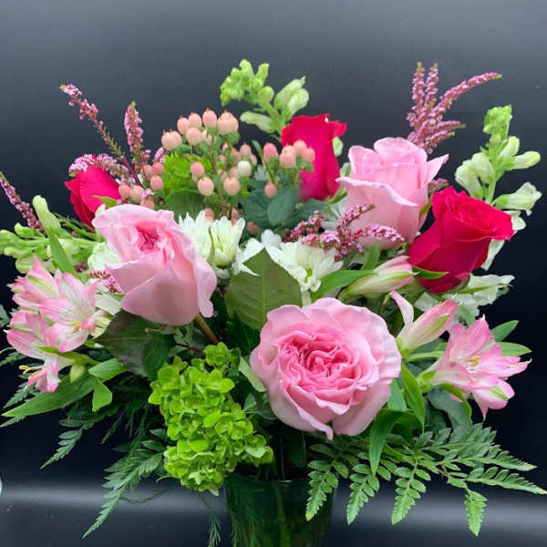 Pink roses and alstroemeria in a green glass vase
