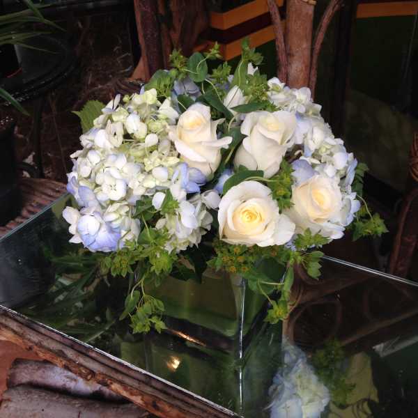 White roses and pale blue hydrangeas in a glass vase