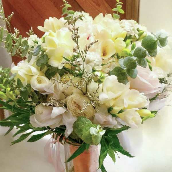 Cream and white bouquet in a clear glass vase with eucalyptus