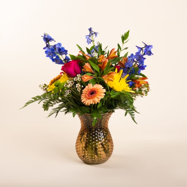 Mixed bouquet of colorful flowers in a hammered glass vase