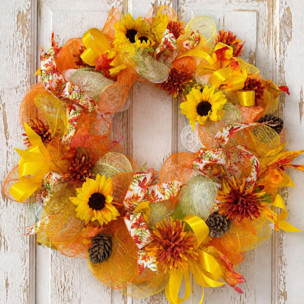 Autumn wreath with sunflowers, orange flowers, ribbons, and pinecones