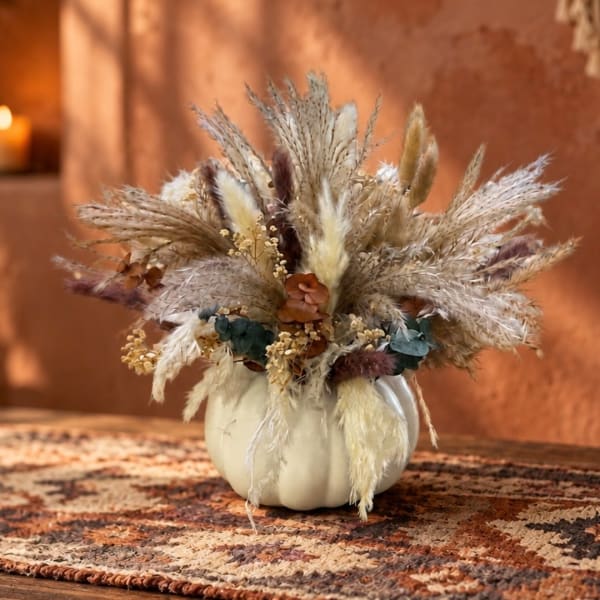 Dried floral arrangement in a white pumpkin vase