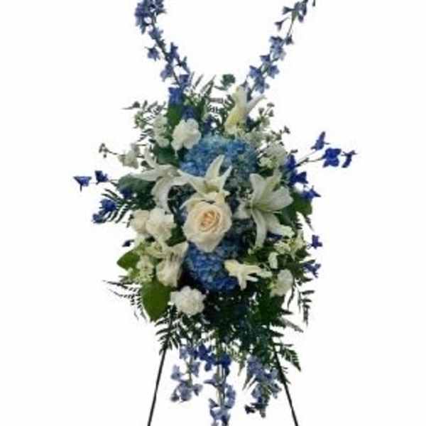 Tall blue and white funeral spray on a stand