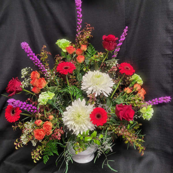 Mixed bouquet in a white vase with red, orange, and white flowers